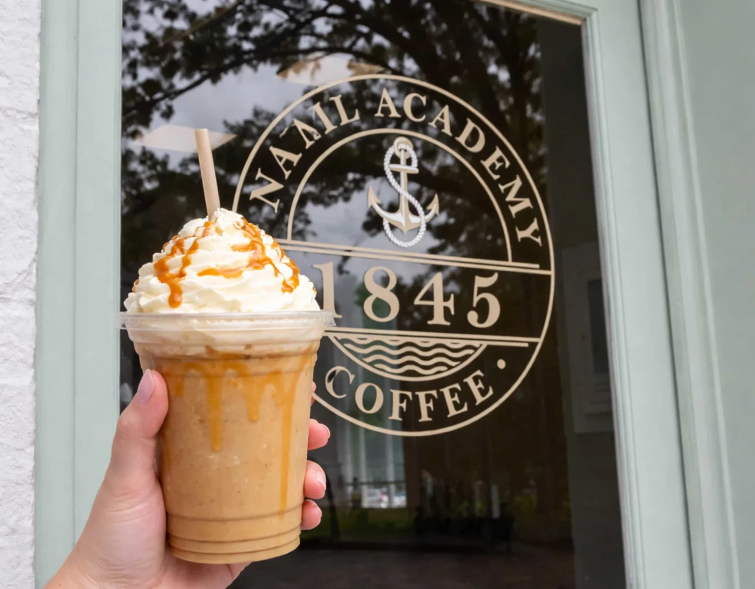 A person holding beverage outside of an 1845 Coffee location