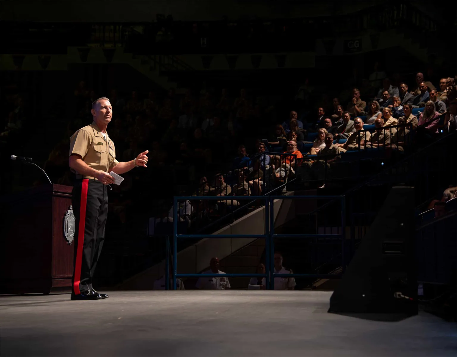 A speaker standing on stage at the USNA Alumni Hall Arena Floor