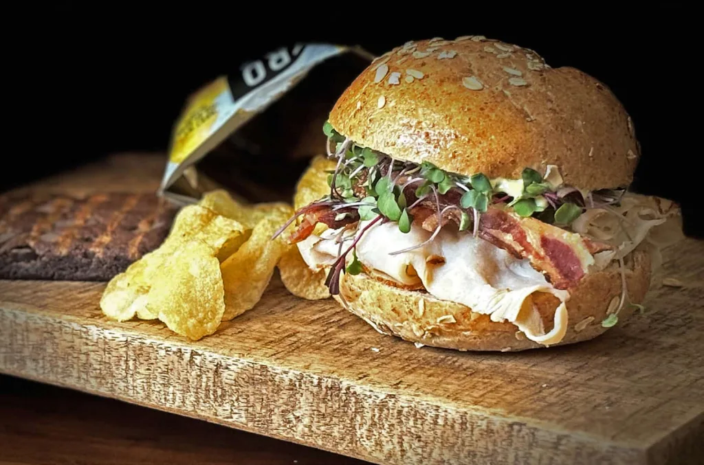 A turkey sandwich with bacon and potato chips